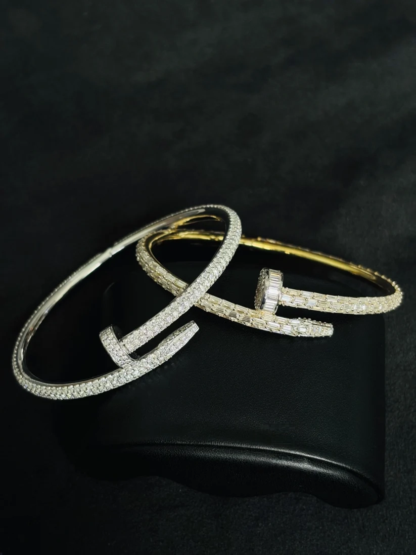 Iced-out silver nail cuff bracelet encrusted with baguette-cut diamonds on a black background