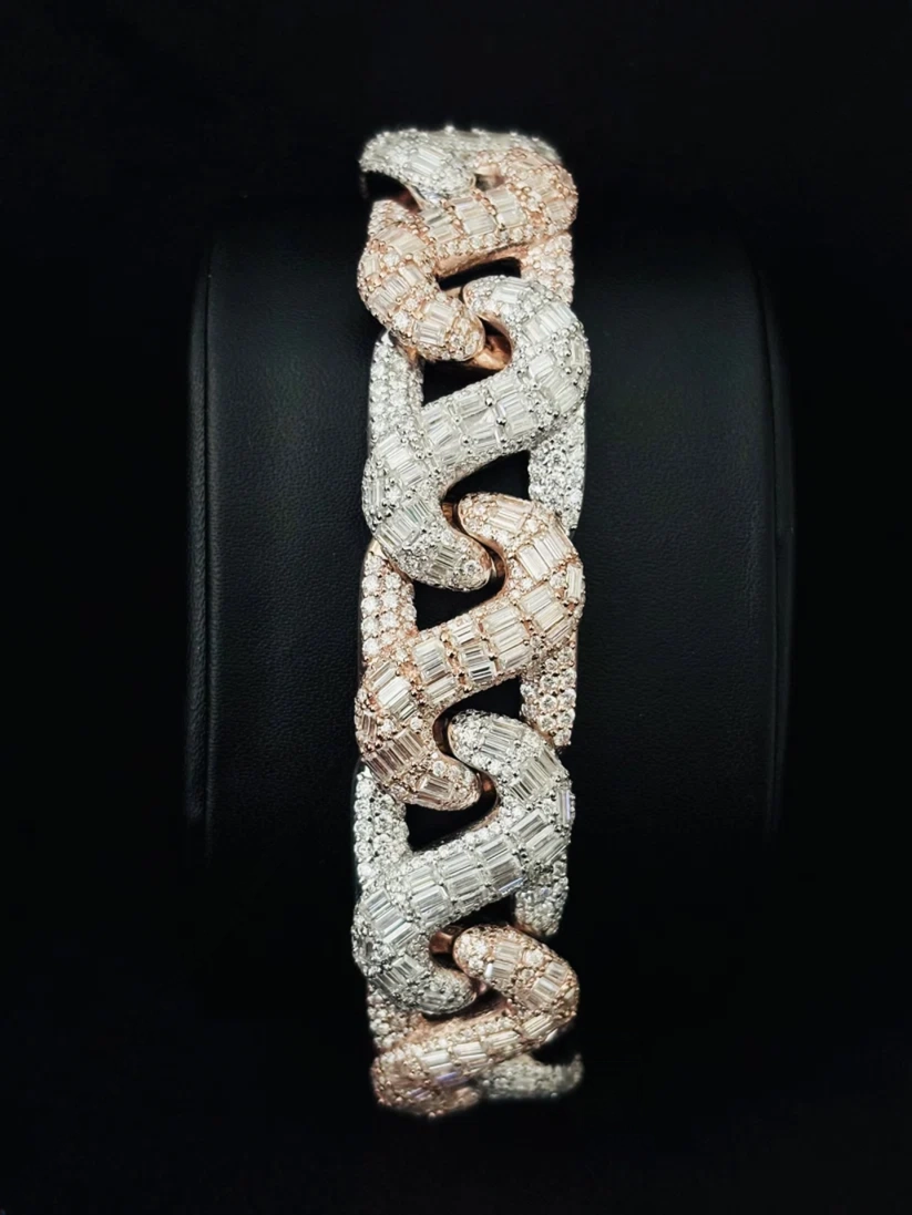A wide, chunky snake-link bracelet in pave-set metal, displayed on a black circular stand