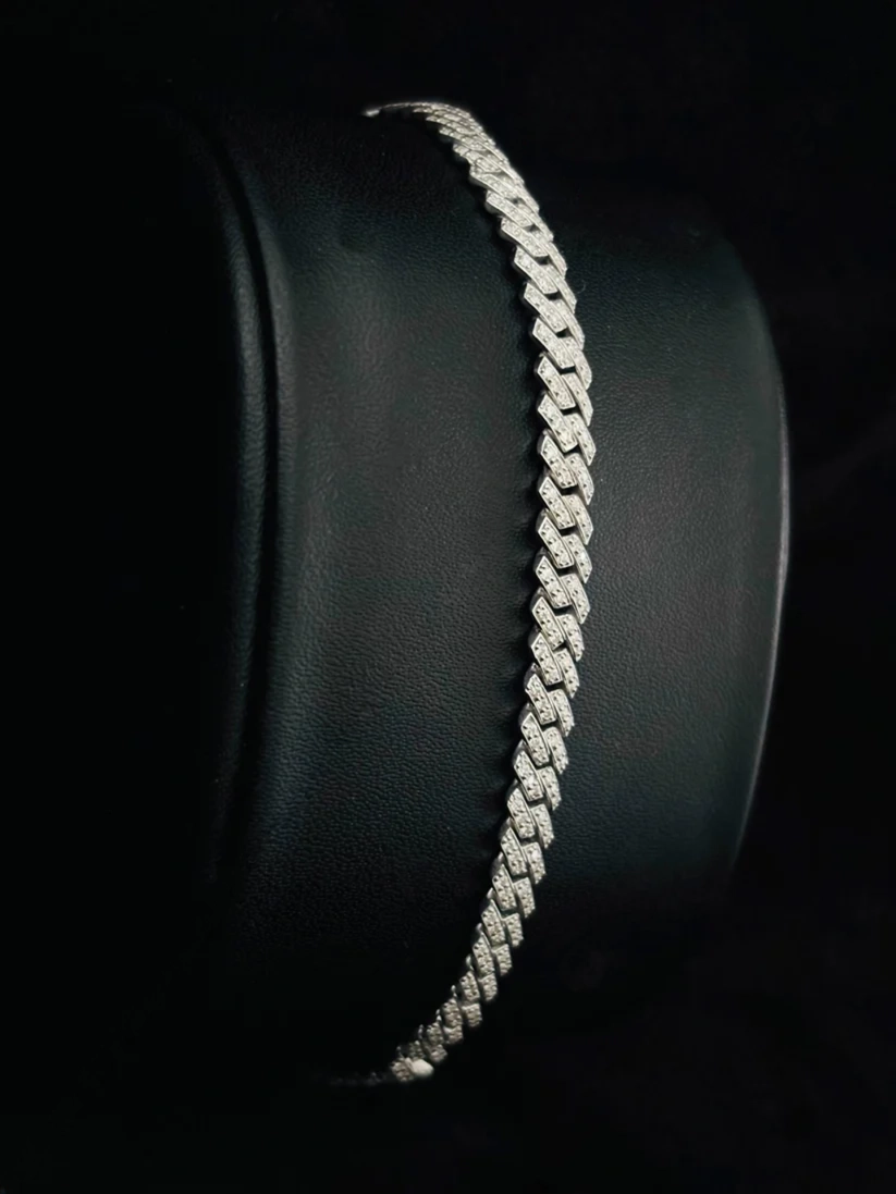 Close up of a sparkling diamond Cuban link chain bracelet against a black background