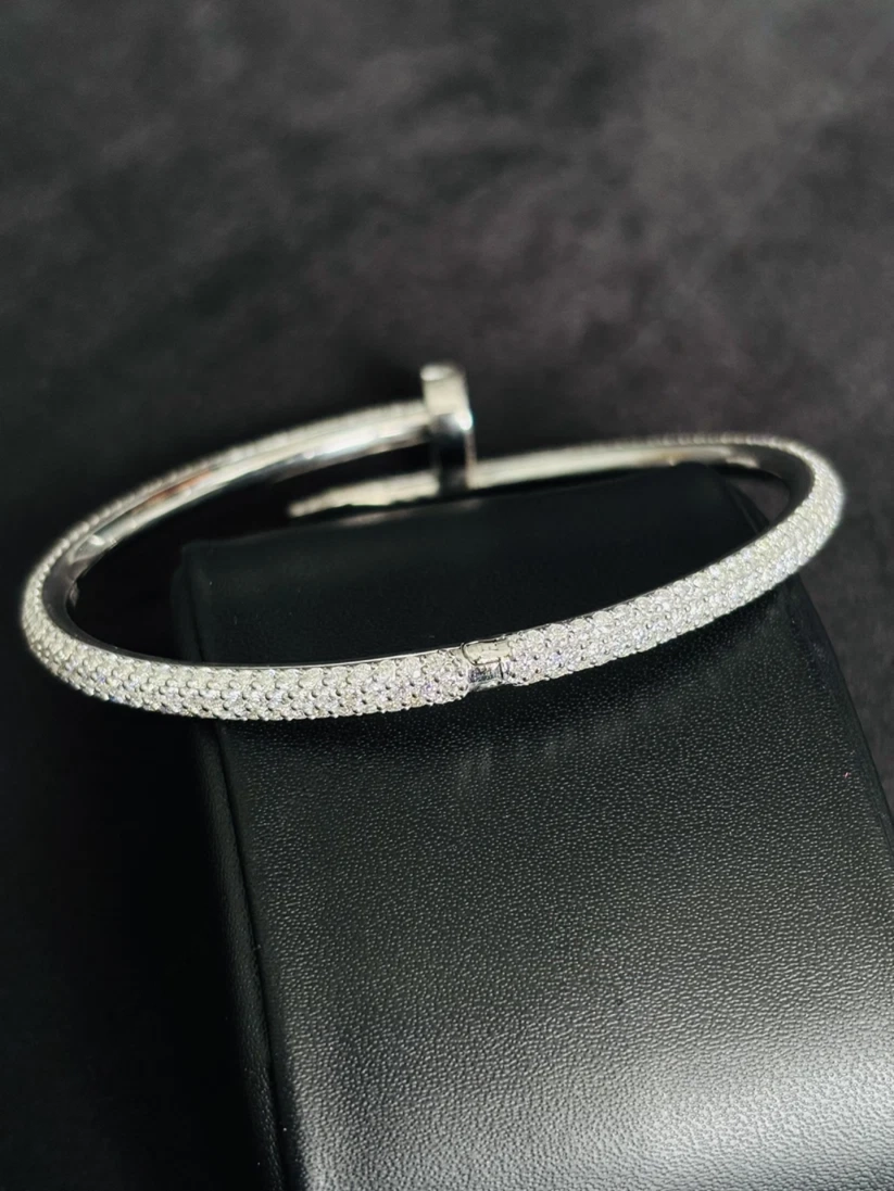 Pave nail-shaped bypass bangle bracelet on a black leather display cushion