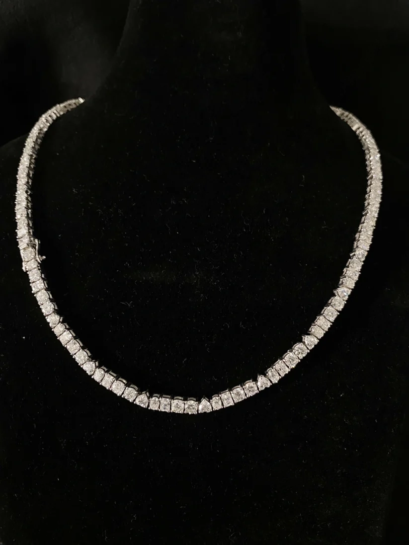 Elegant diamond tennis necklace displayed on a black jewelry stand