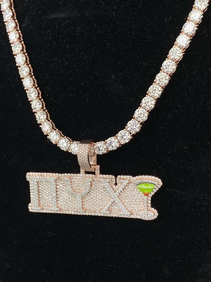 A close-up view Custom iced out πYX letters pendant on a tennis chain against a black background