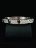 A close-up view silver bangle bracelet with a pave-set diamond band and three screw-head accents