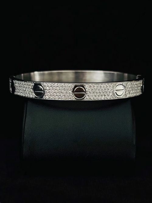 A close-up view silver bangle bracelet with a pave-set diamond band and three screw-head accents