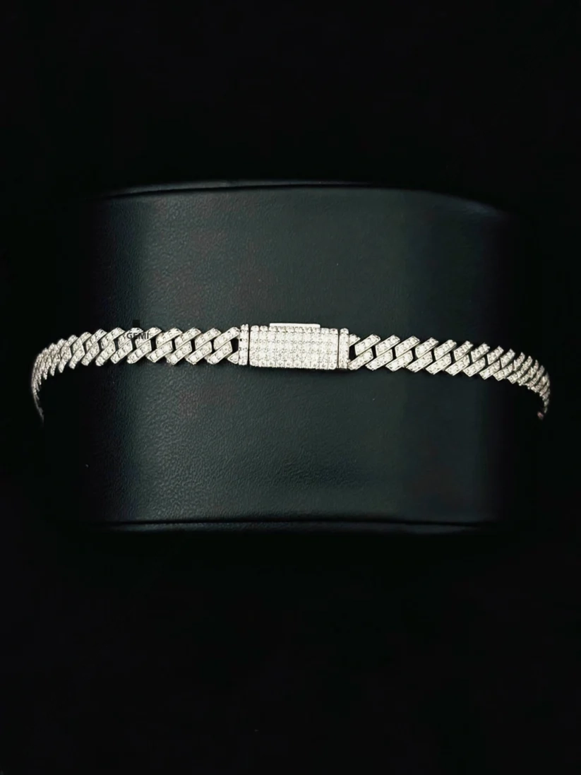 Close-up of a shimmering silver iced-out Cuban link bracelet on a black display stand