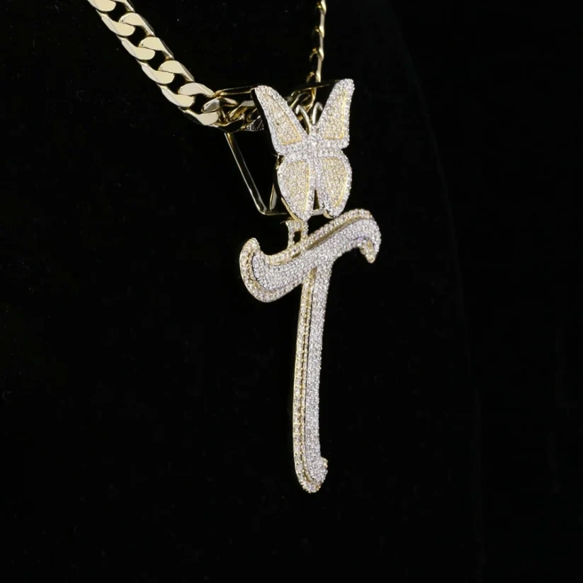 Gold cuban link chain with an iced-out letter T pendant and crystal butterfly accent