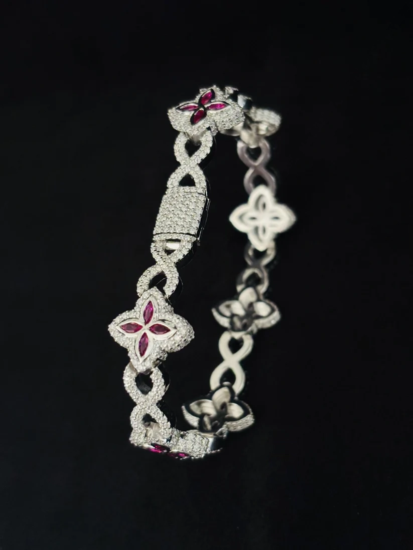 Diamond infinity link bracelet with ruby four-leaf clover motifs in silver