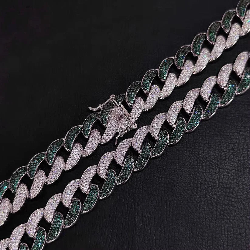 Close-up of a luxury iced-out Cuban link necklace featuring alternating rows of green emeralds and white diamonds