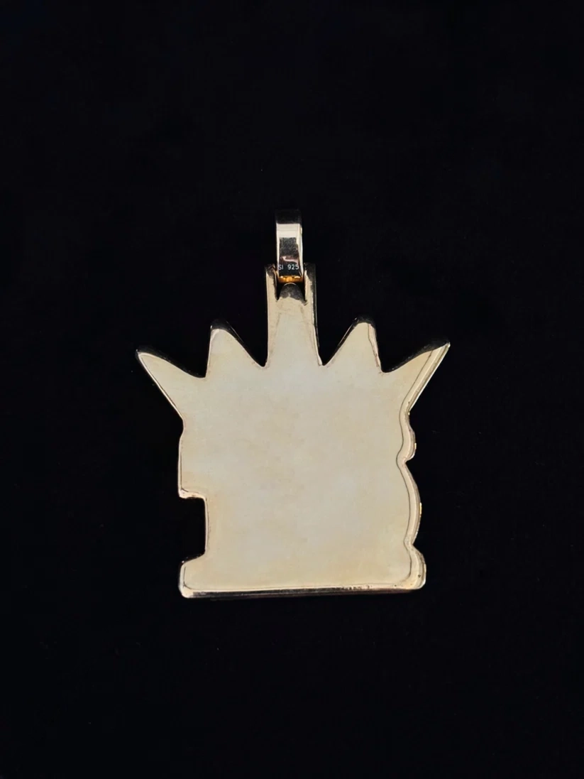 Back view of a gold crown-shaped pendant charm on a black background