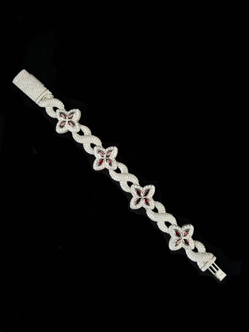 Iced out silver infinity link bracelet with red clover motif