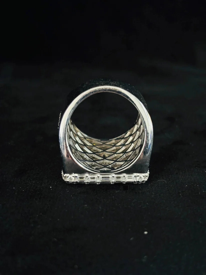 A silver ring with a wide, textured basketweave band and a encrusted flat base