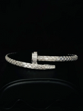 Iced-out silver nail cuff bracelet encrusted with baguette-cut diamonds on a black background