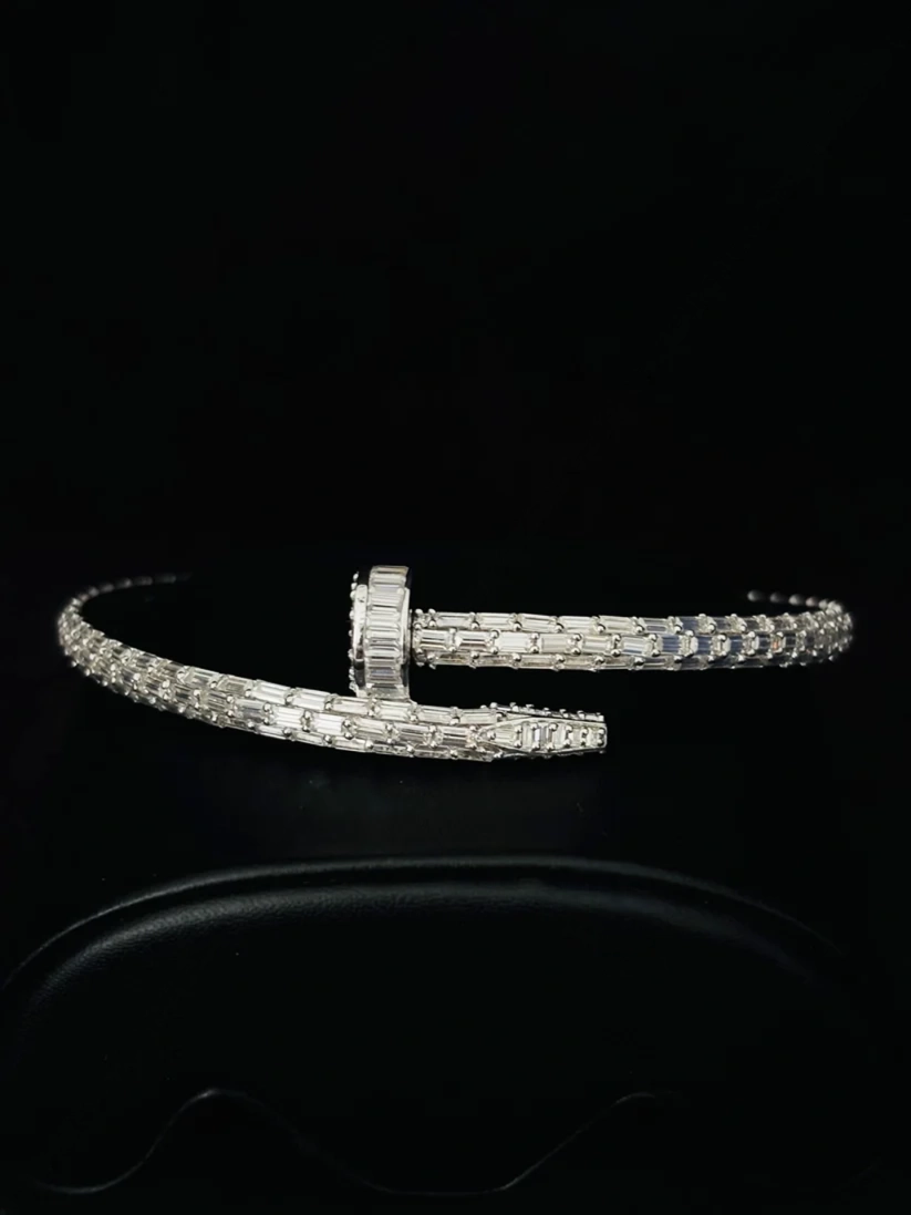 Iced-out silver nail cuff bracelet encrusted with baguette-cut diamonds on a black background