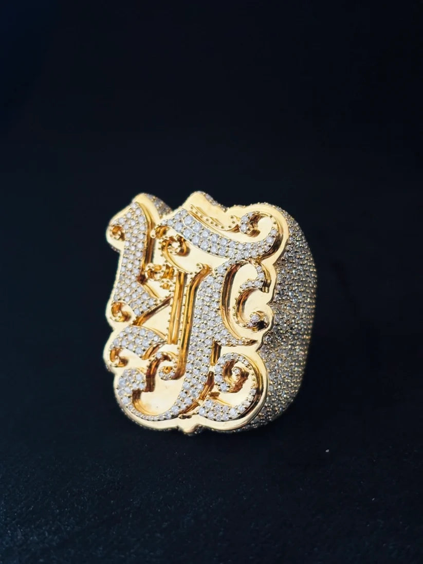 An ornate initial ring featuring a large decorative letter 'J' paved with diamond