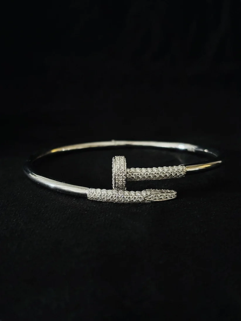 cuff bracelet featuring a central T-shaped bar pave-set with diamond photographed on a dark black background