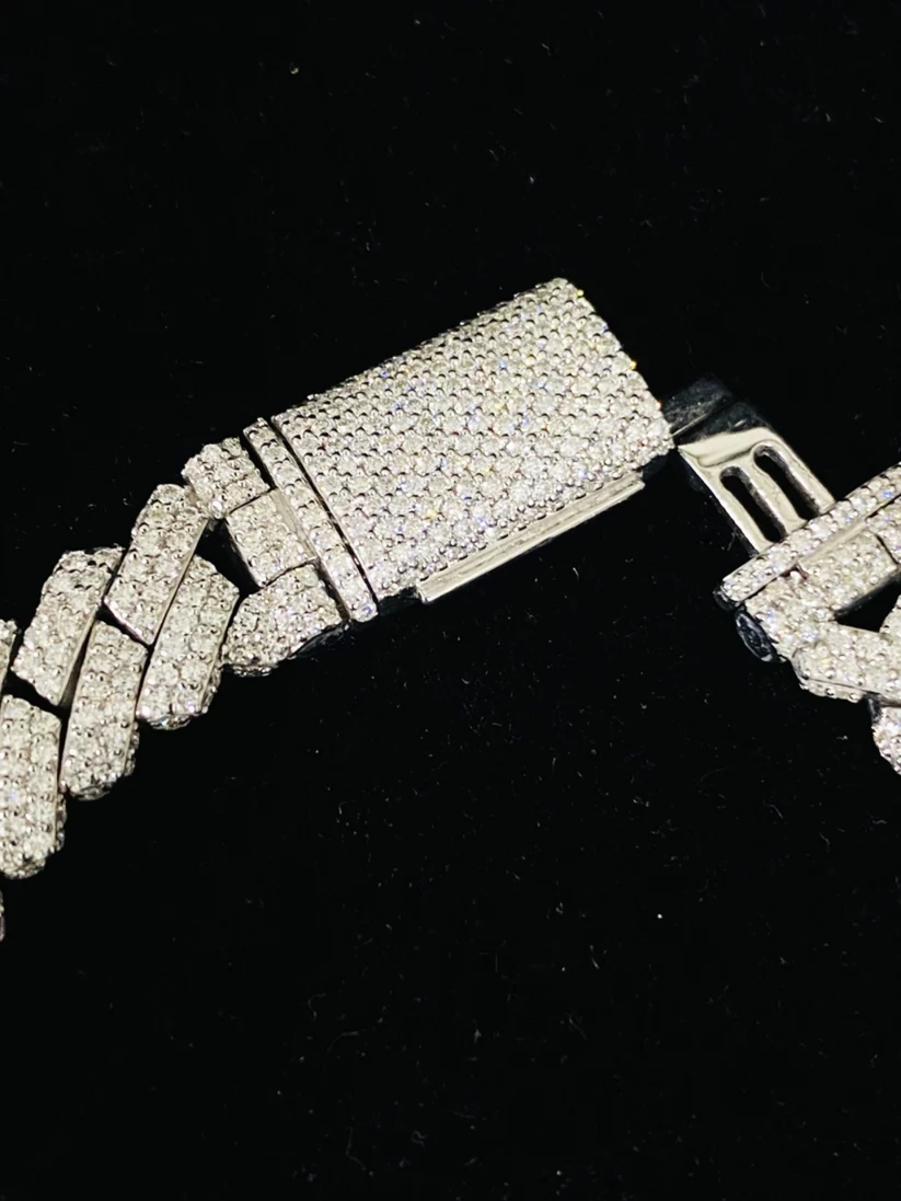 A close-up of a silver bracelet with a heavily paved rectangular clasp and matching pave links