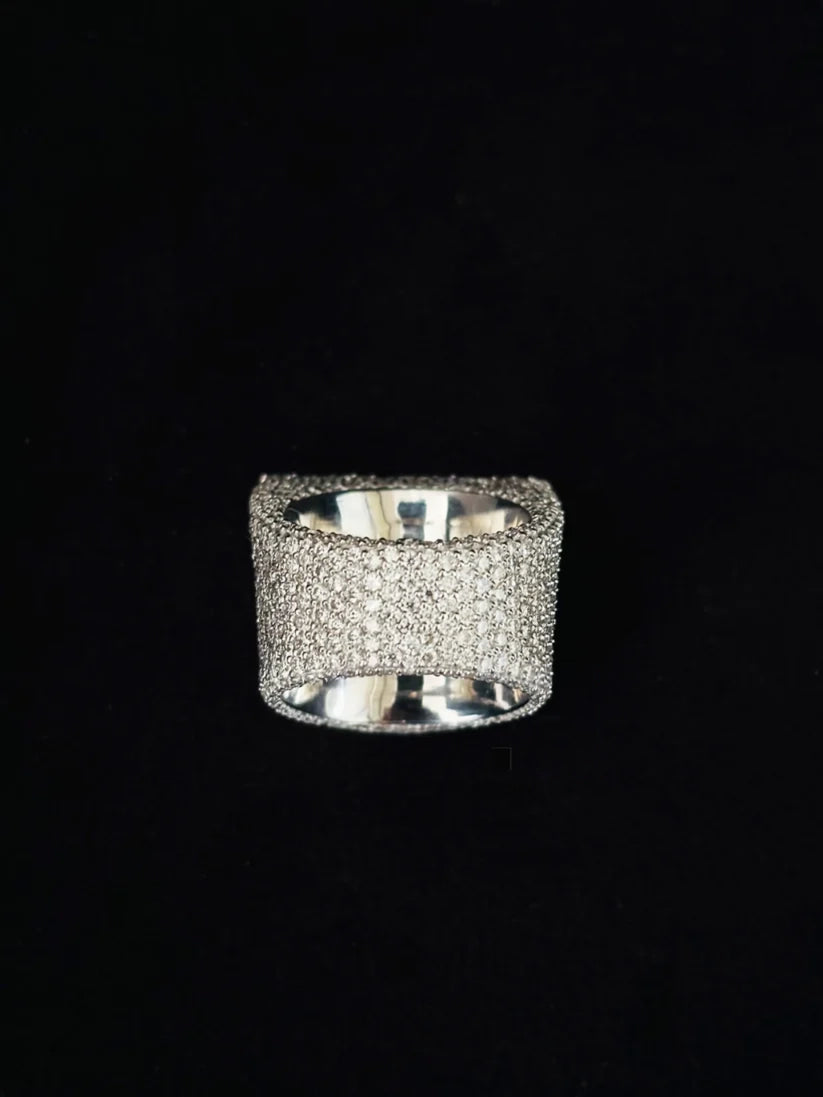 A wide silver band ring heavily embellished with small clear pave stones