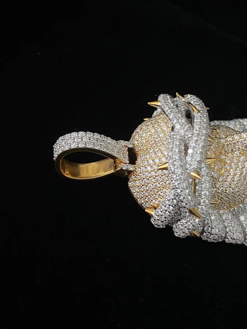 Close-up of a custom diamond heart pendant wrapped in a diamond crown of thorns with gold spikes against a black background.