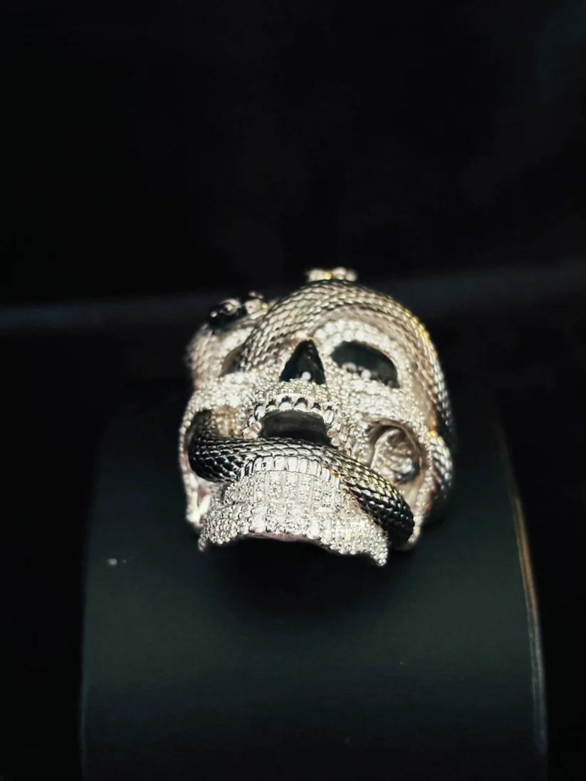 Diamond encrusted skull pendant with a black and silver pave snake coiled through the eye socket and jaw