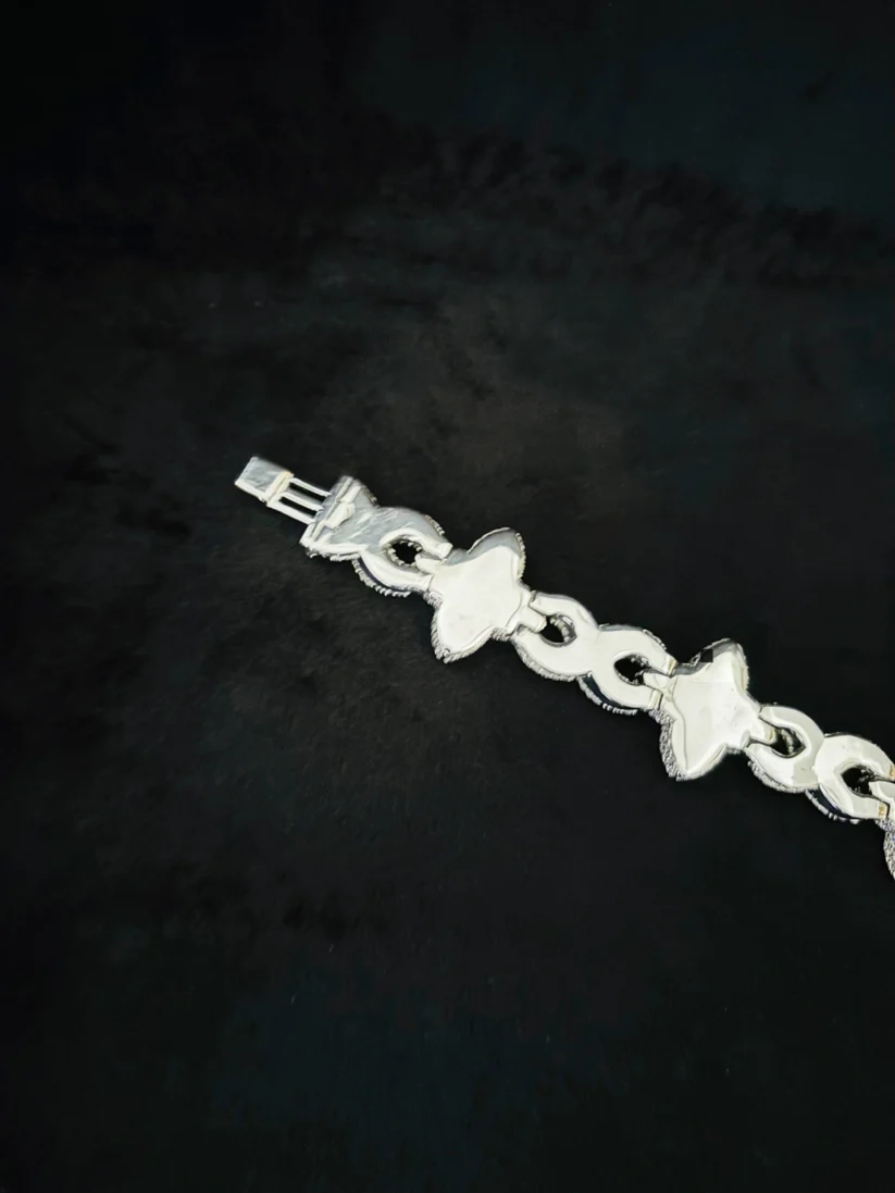 Silver infinity link and clover charm bracelet on black background