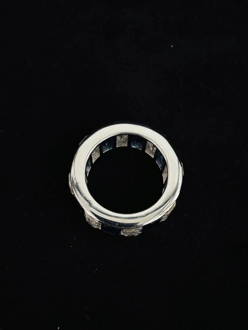 A silver ring with a wide eternity band and a central dark inlay diamonds 