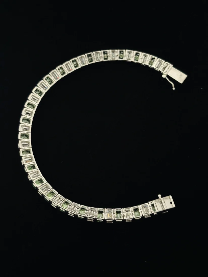 Luxury tennis bracelet featuring alternating emerald-cut green gemstones and white diamonds set in silver