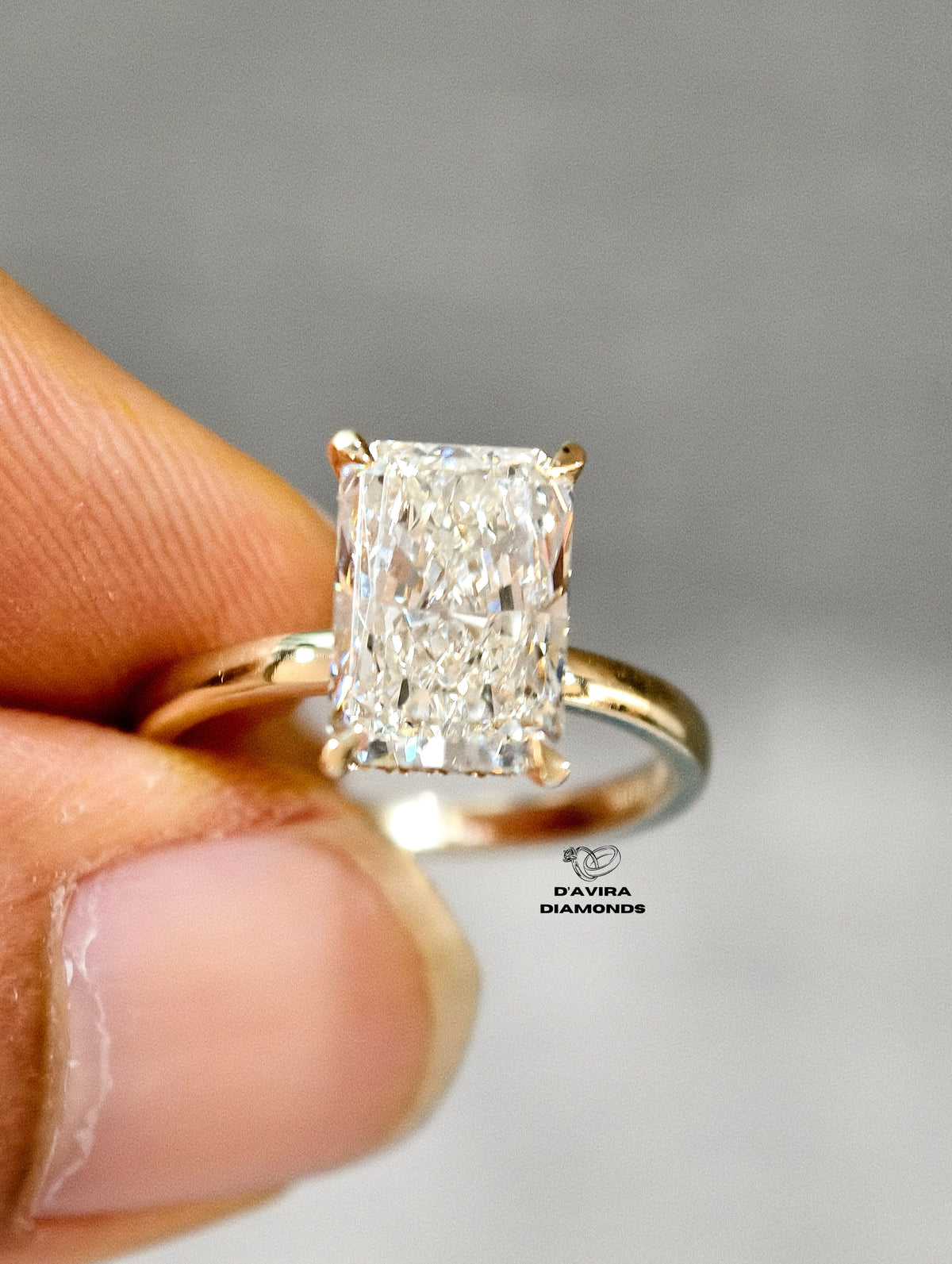 A close-up of a diamond ring held between fingers