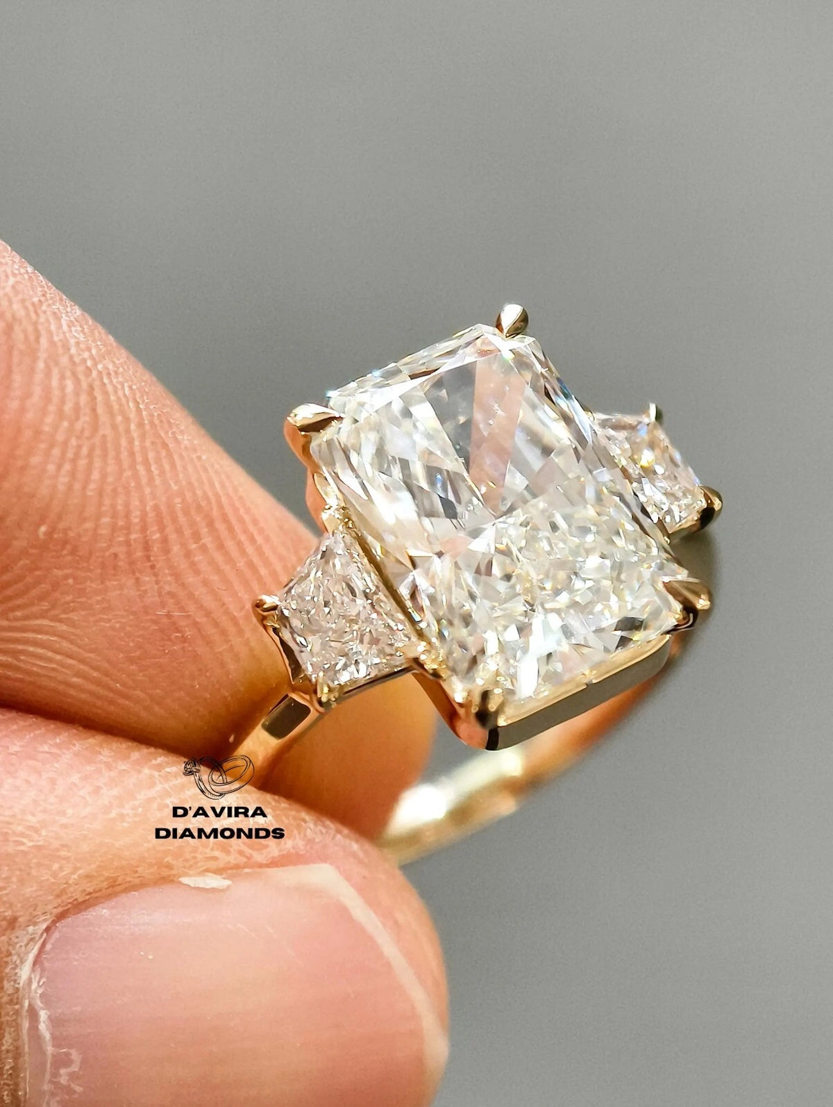 A close-up of a diamond ring held between finger