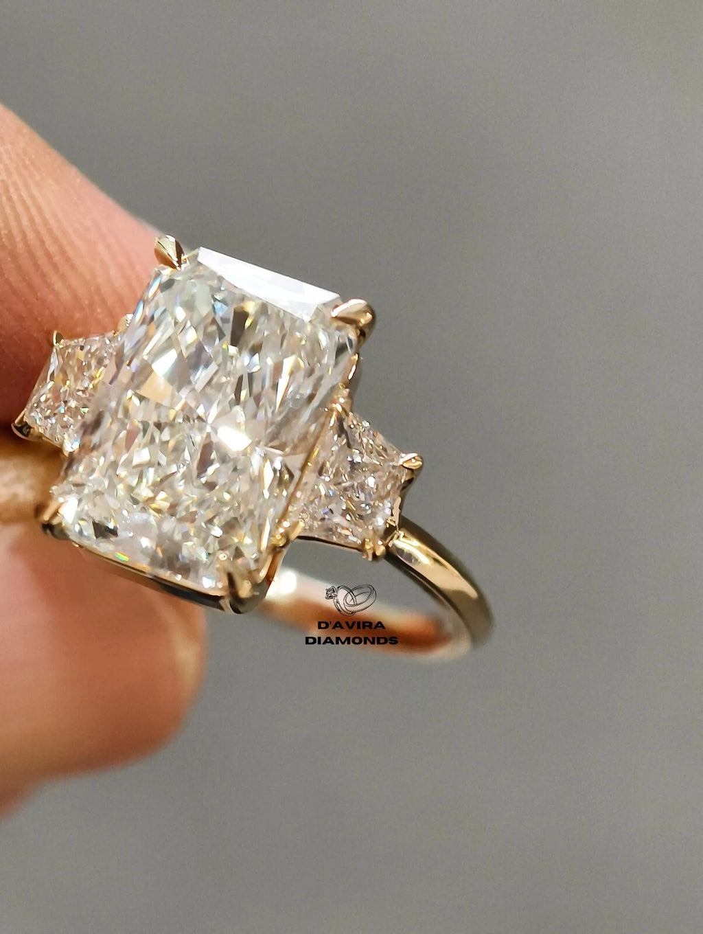 Radiant cut diamond ring with trapezoid side stones in yellow gold.