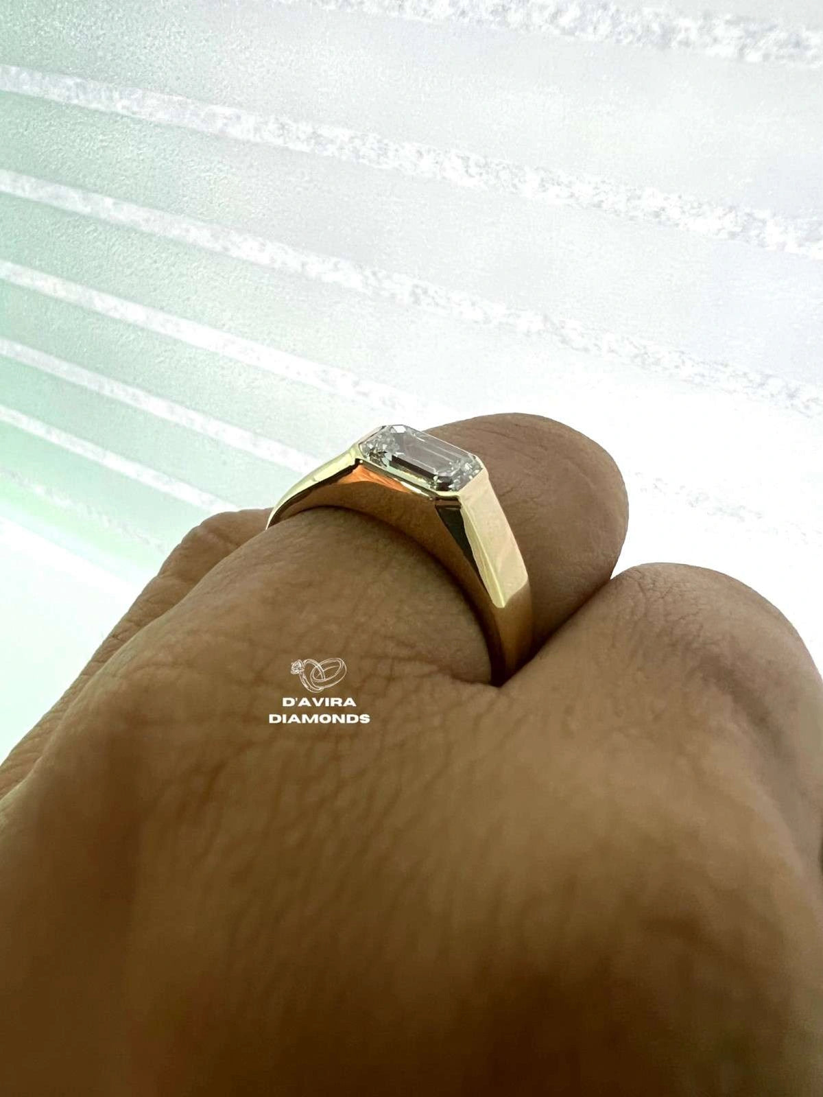 side view of an emerald cut lab grown diamond bezel set ring on finger