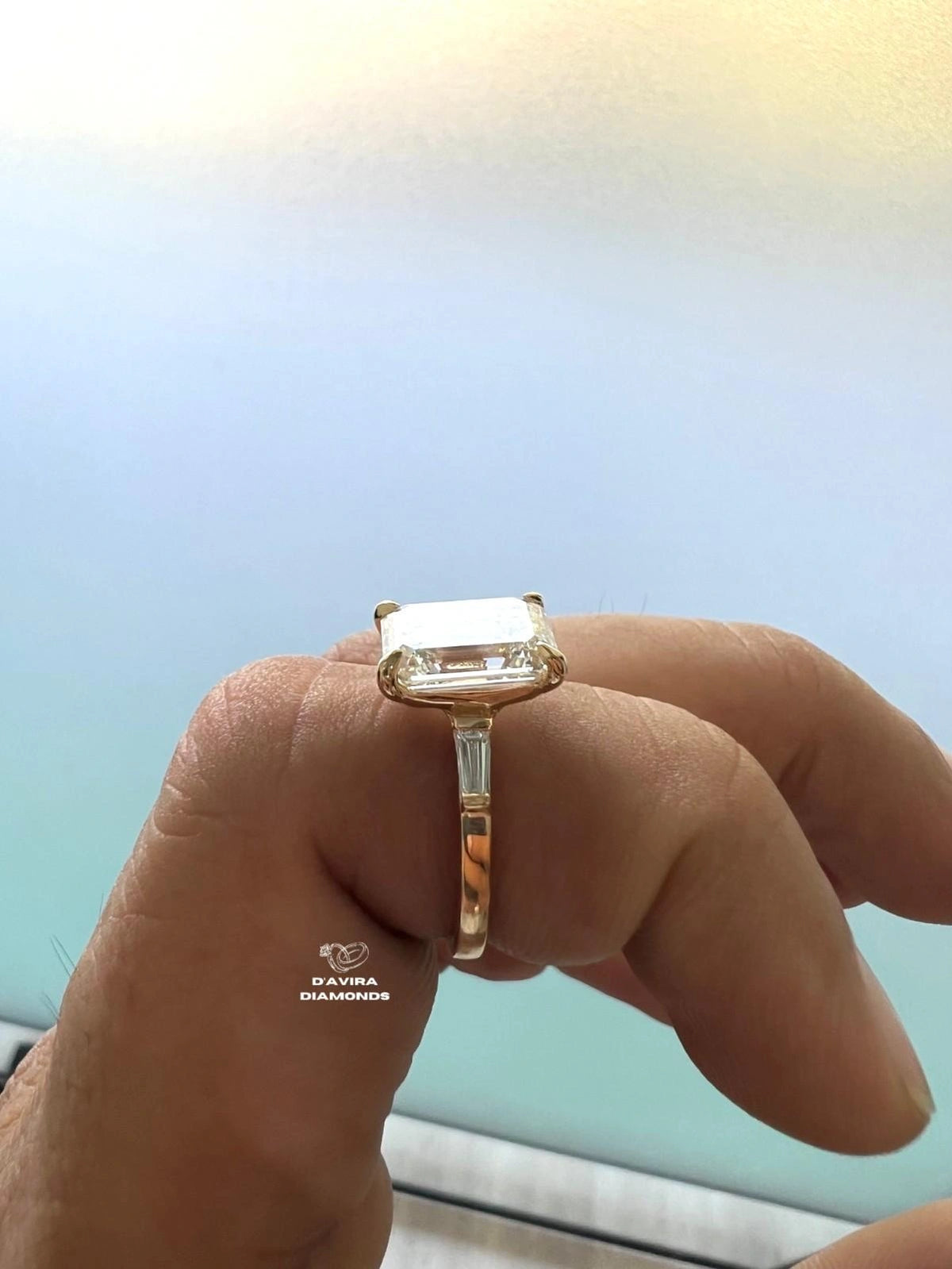 A close-up side view of a hand wearing a yellow gold ring 