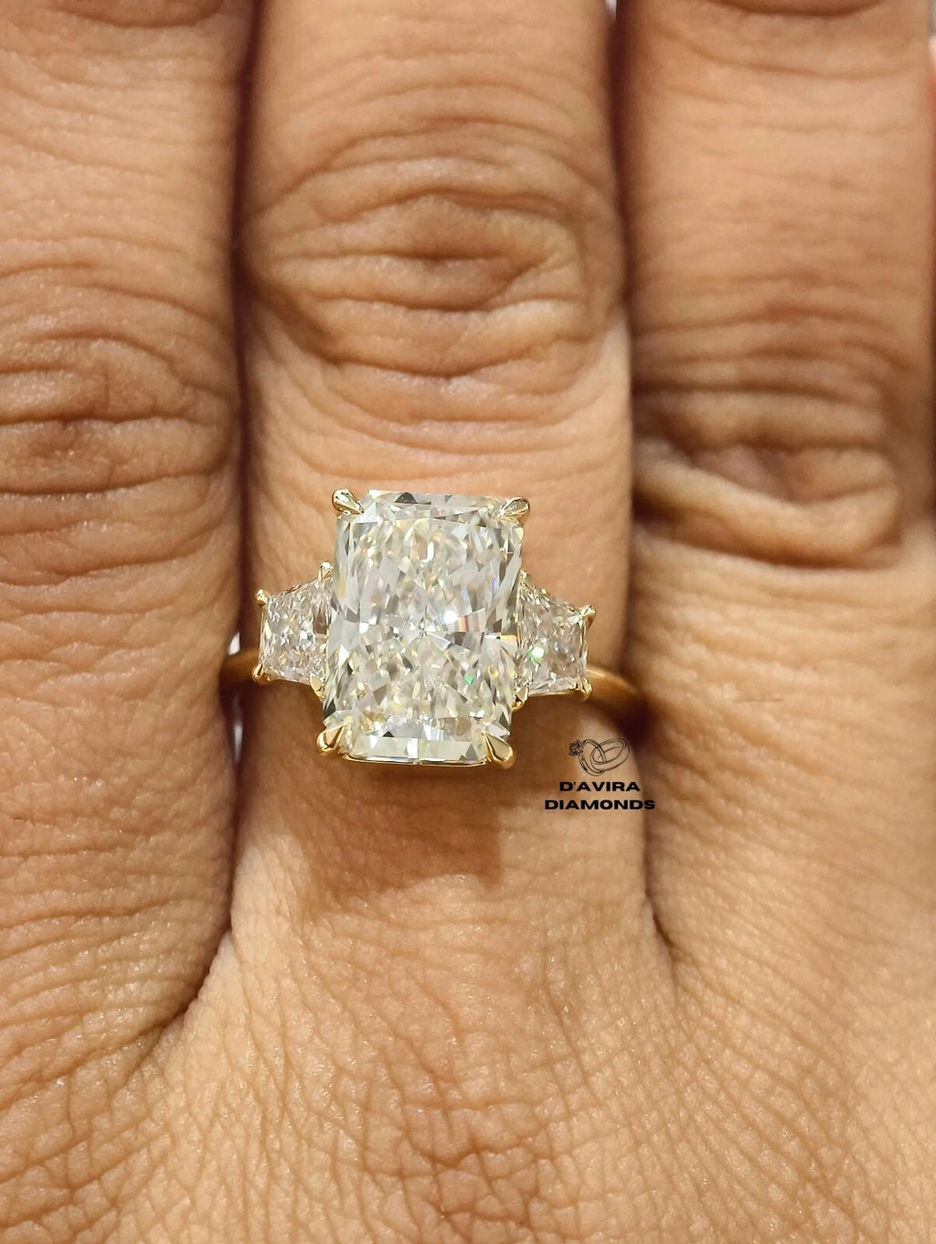 Three-stone radiant cut diamond ring worn on a finger
