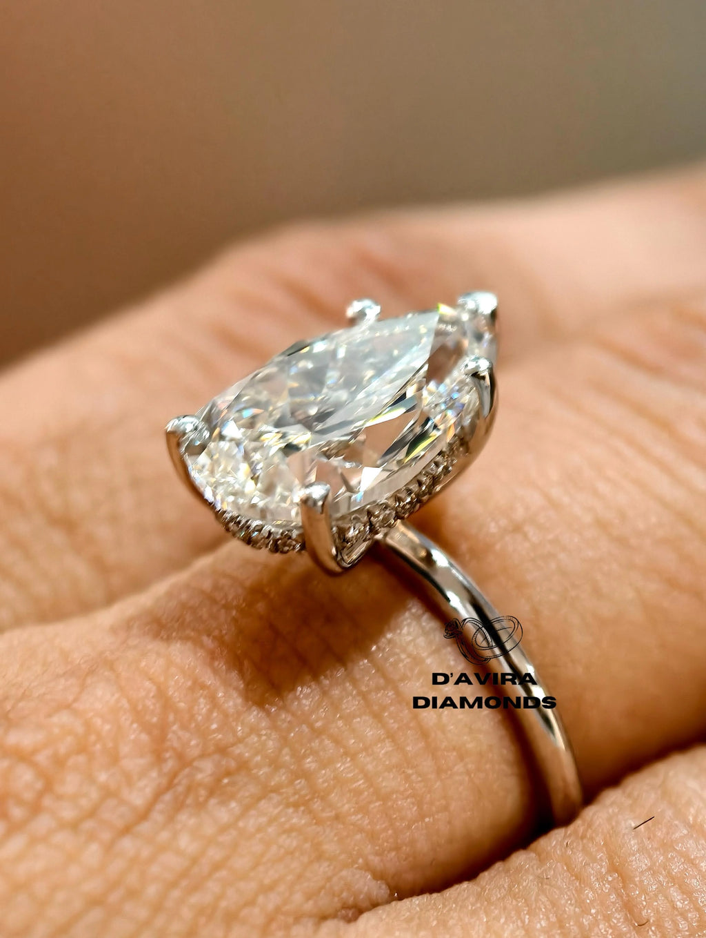 A close-up of a gold ring with a pear-cut worn on a finger
