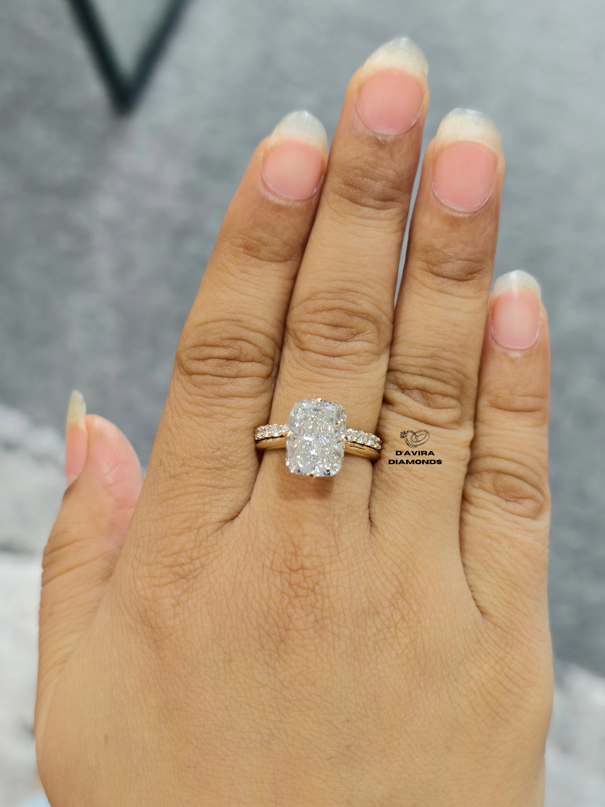 Elongated cushion cut diamond engagement ring with pave gold band on hand