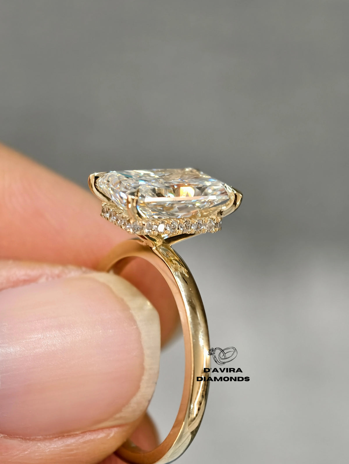 A close-up of a gold ring with a radiant-cut diamond and smaller accent diamond