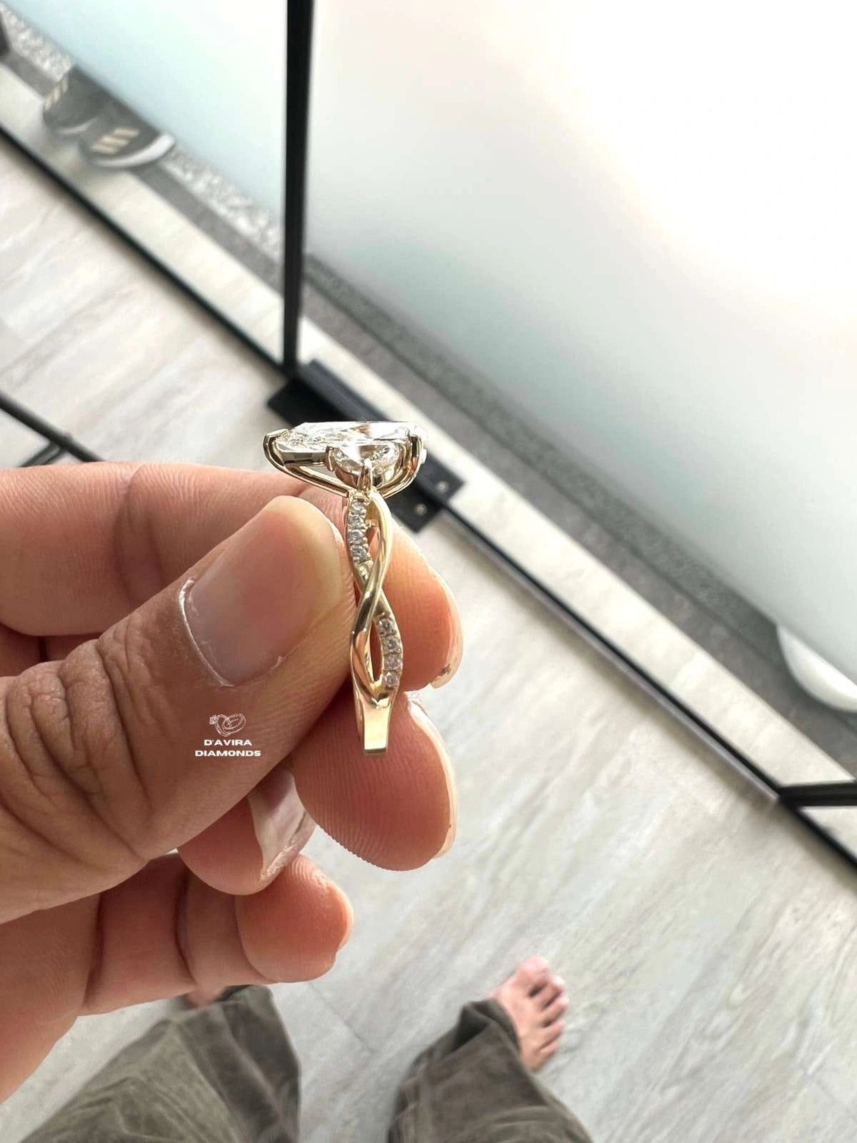 A hand holding a twisted gold engagement ring