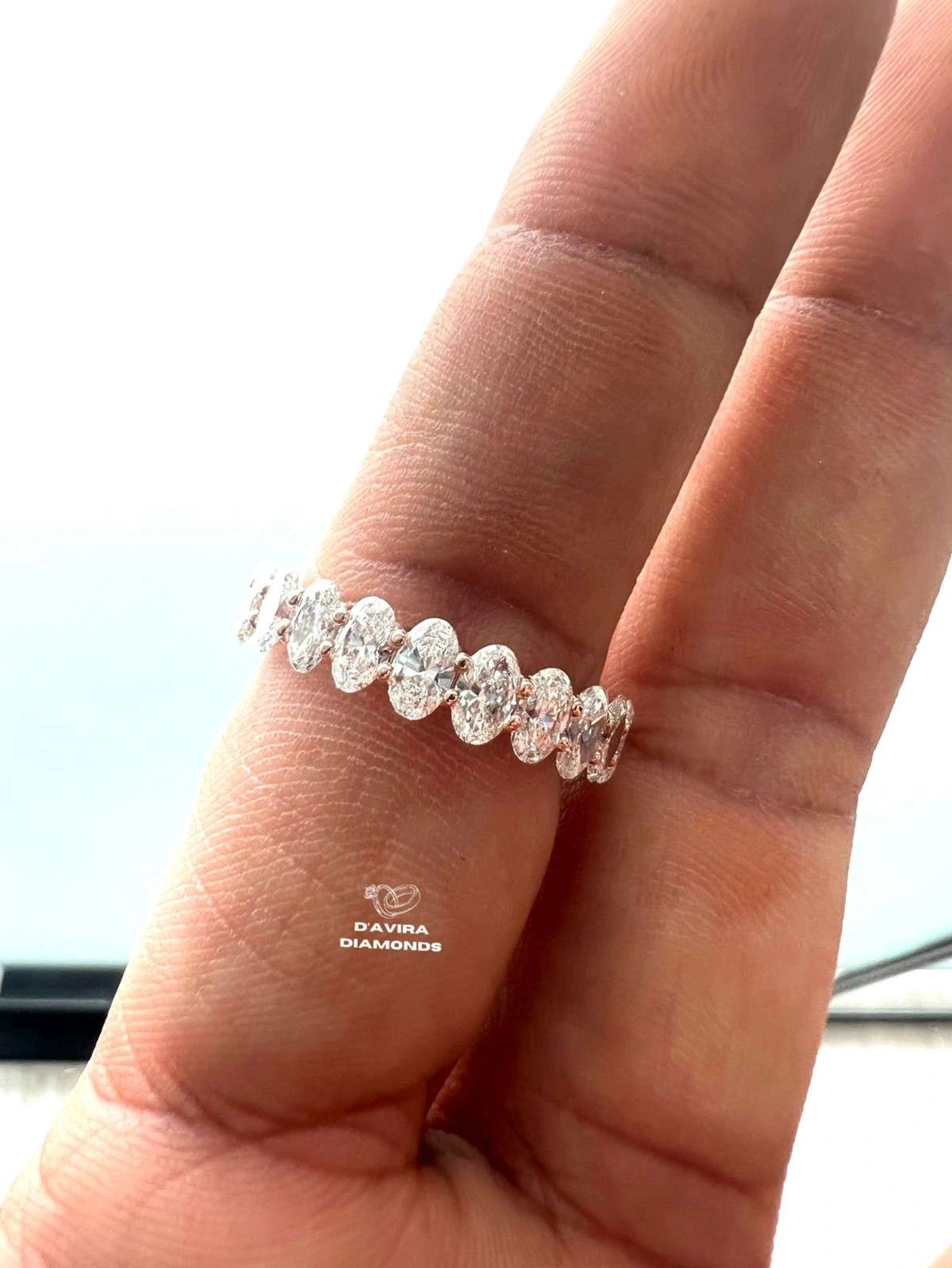 front view of a hand wearing a diamond eternity ring row of oval-cut diamonds set