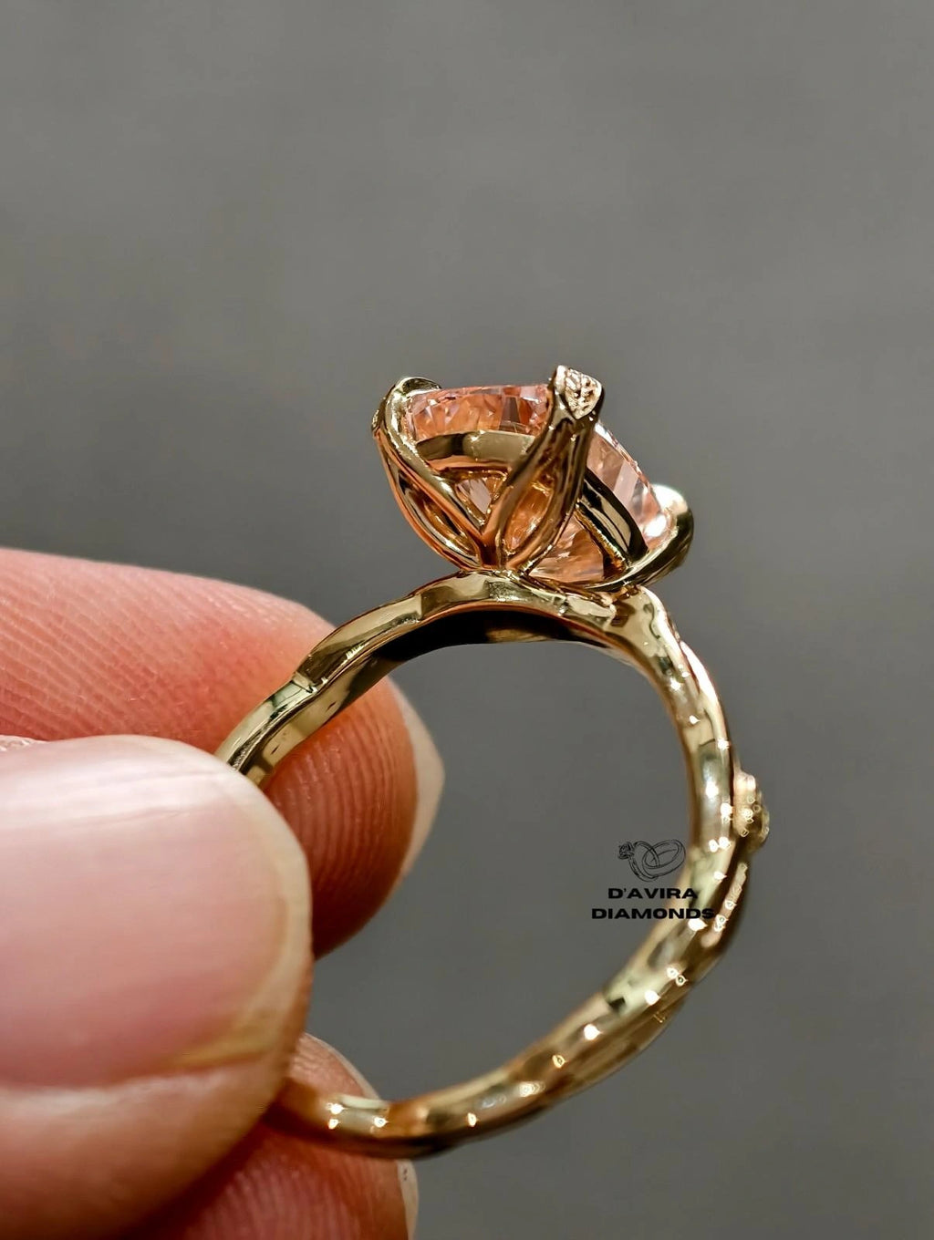 A close-up of a gold ring held between finger radiant cut diamond ring