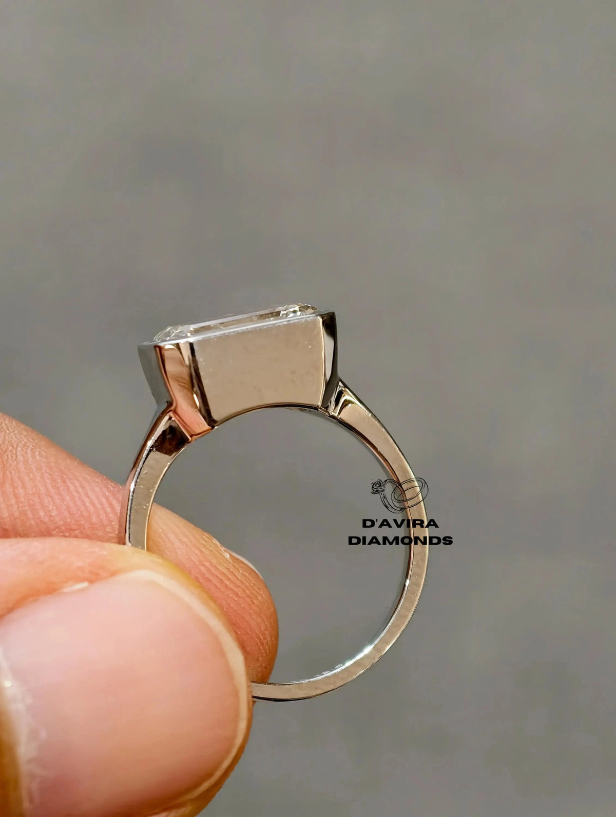 A close-up of a diamond ring setting held between finger