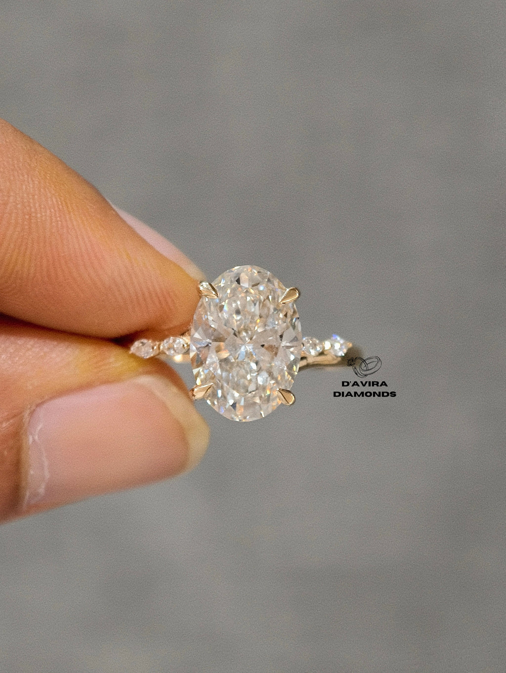 oval solitaire diamond ring in 14k gold with accent side stones on a band.