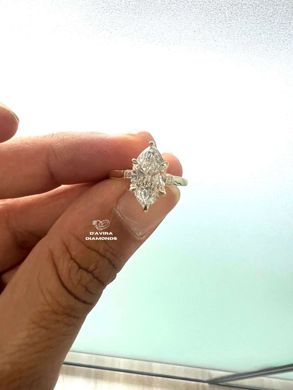 Lab grown marquise cut diamond engagement ring held in a hand