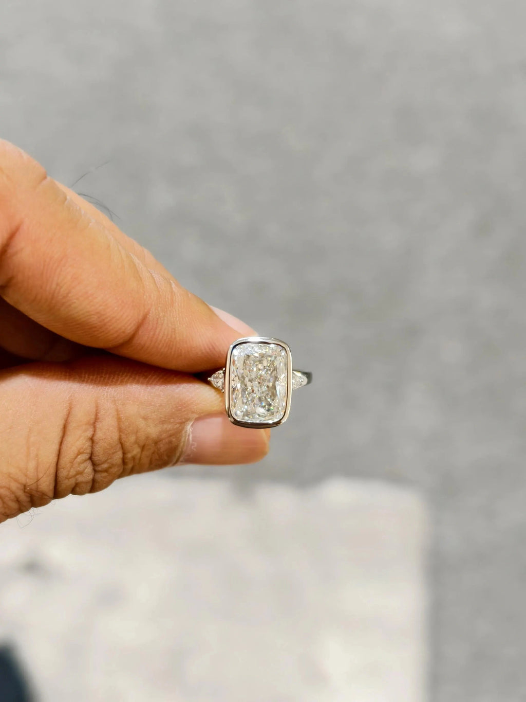 hand holding side stone cushion cut lab grown diamond ring