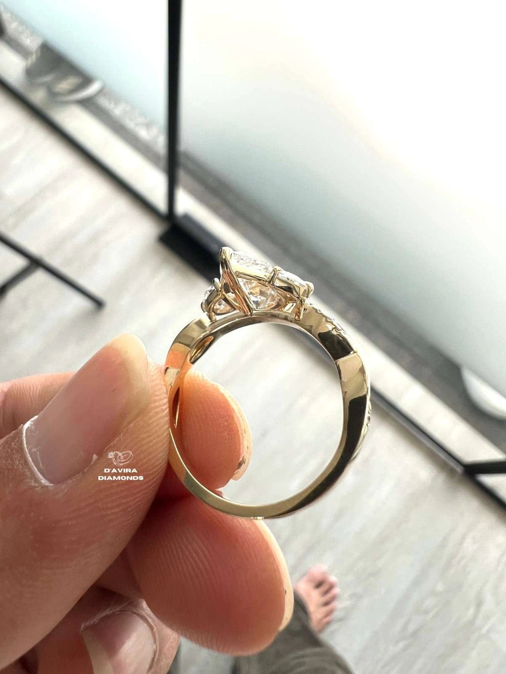 A close-up of a lab grown diamond ring held between fingers