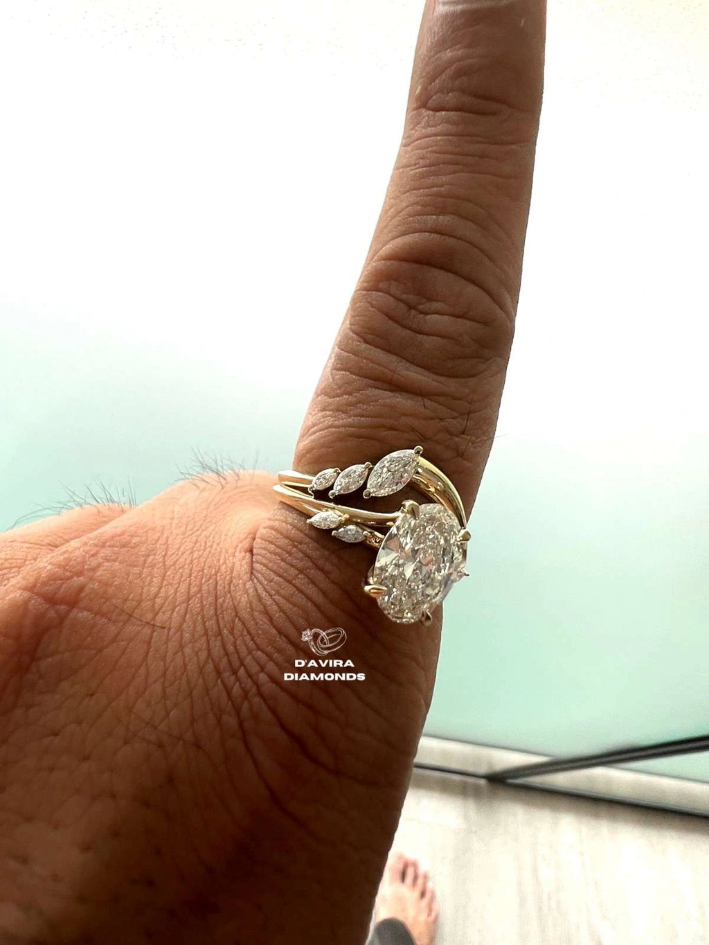 side view of a person finger wearing a yellow gold ring set with marquise-cut diamond