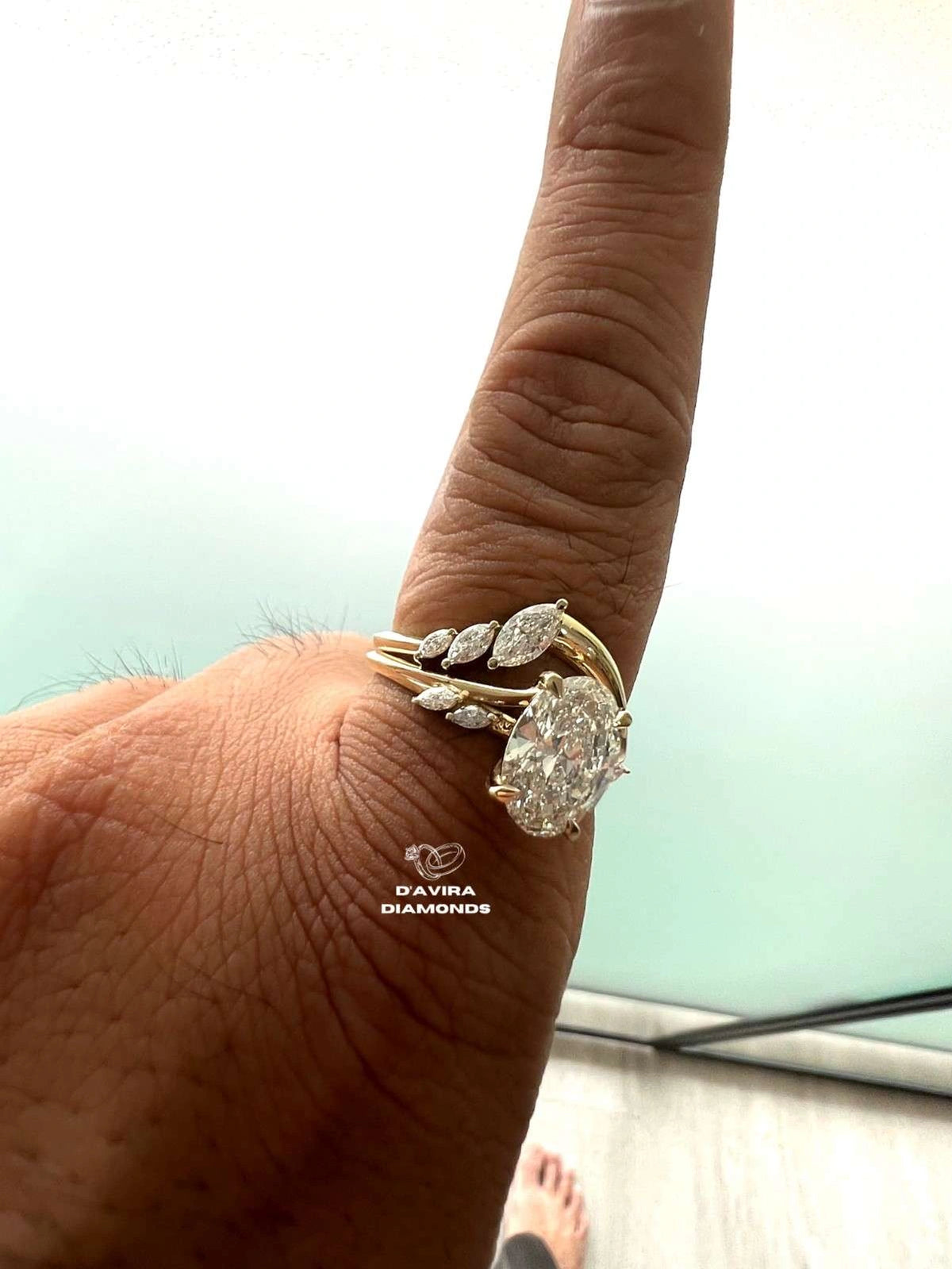 side view of a person finger wearing a yellow gold ring set with marquise-cut diamond