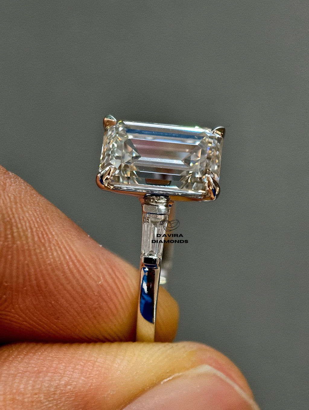 Side view of a diamond ring showing the basket set, band thick, and tapered baguette side stone