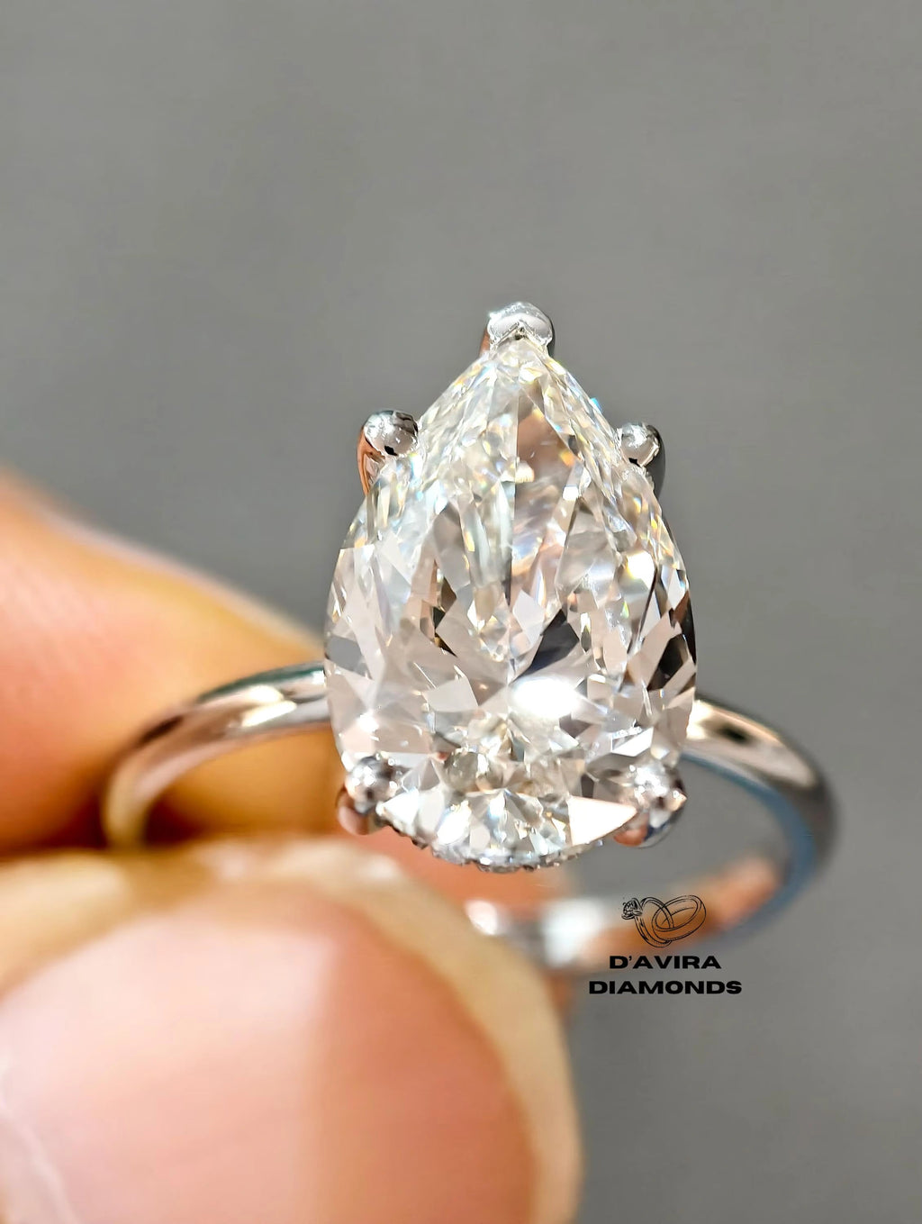 A pear-cut diamond ring held between fingers 