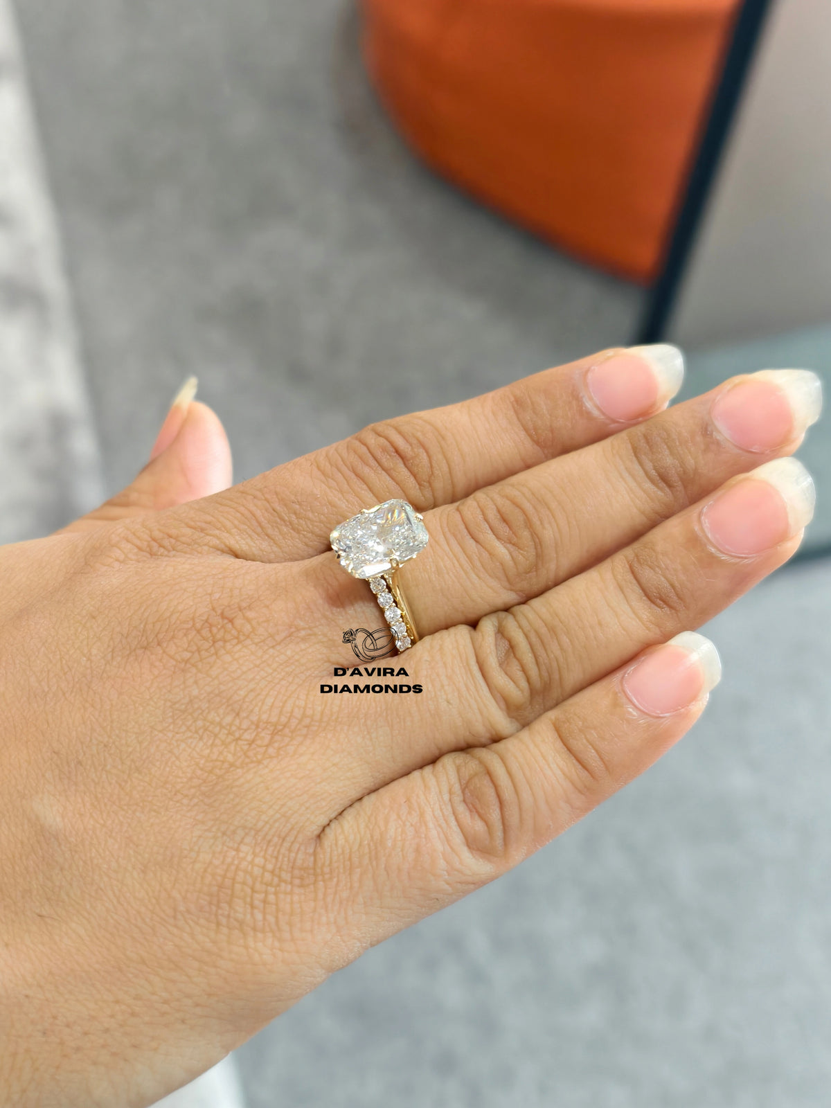 A close-up of a hand wearing a diamond engagement ring with a cushion-cut